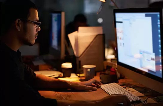 A focused individual working diligently on a computer, immersed in their tasks.