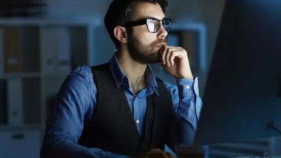 a person in specs working on a computer in a room