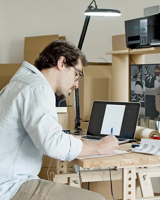 a person working on laptop and taking notes